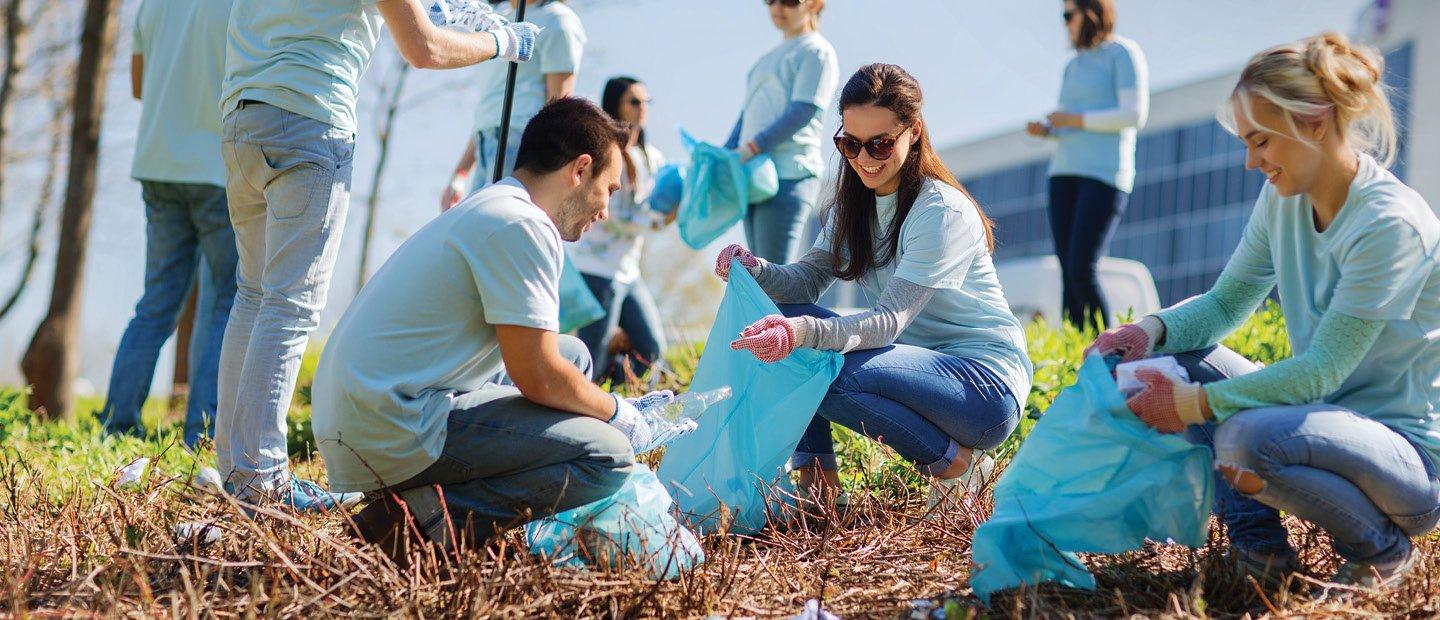 A group of people collecting trash in blue bags outdoors.